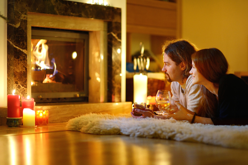 Happy couple having drinks by a fireplace